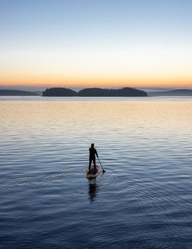 Paddler on Vancouver Island ocean with sunset in the background